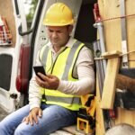 Construction worker using smartphone near the construction site